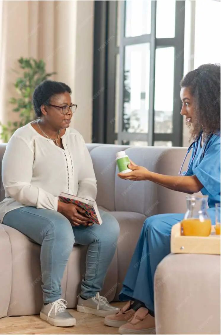 A caregiver hands a medication bottle to a client at home